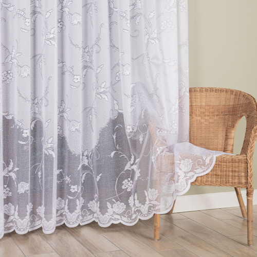 Długa firanka żakardowa (230 lub 250 cm) w białe kwiaty, z przybliżeniem na misterny wzór i laserowo wykończoną, falistą krawędzią na dole.