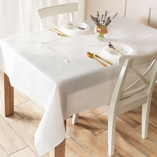 Elegancki biały obrus Modena z koronkową gipiurą rozłożony na drewnianym stole w jadalni.