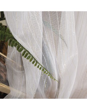alt="Delikatna firana z nabłyszczanej przędzy w kolorze białym, ozdobiona złotą nitką. Firanka o wysokości 300 cm elegancko układa się w miękkie fałdy i subtelnie odbija światło, tworząc efekt lekkości i blasku. Idealna do wysokich pomieszczeń i nowoczes